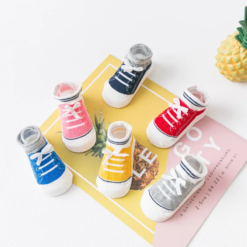 Colorful 3D shoe-style anti-slip baby socks with silicone grip soles, displayed in pink, red, yellow, blue, gray, and navy for toddlers and infants